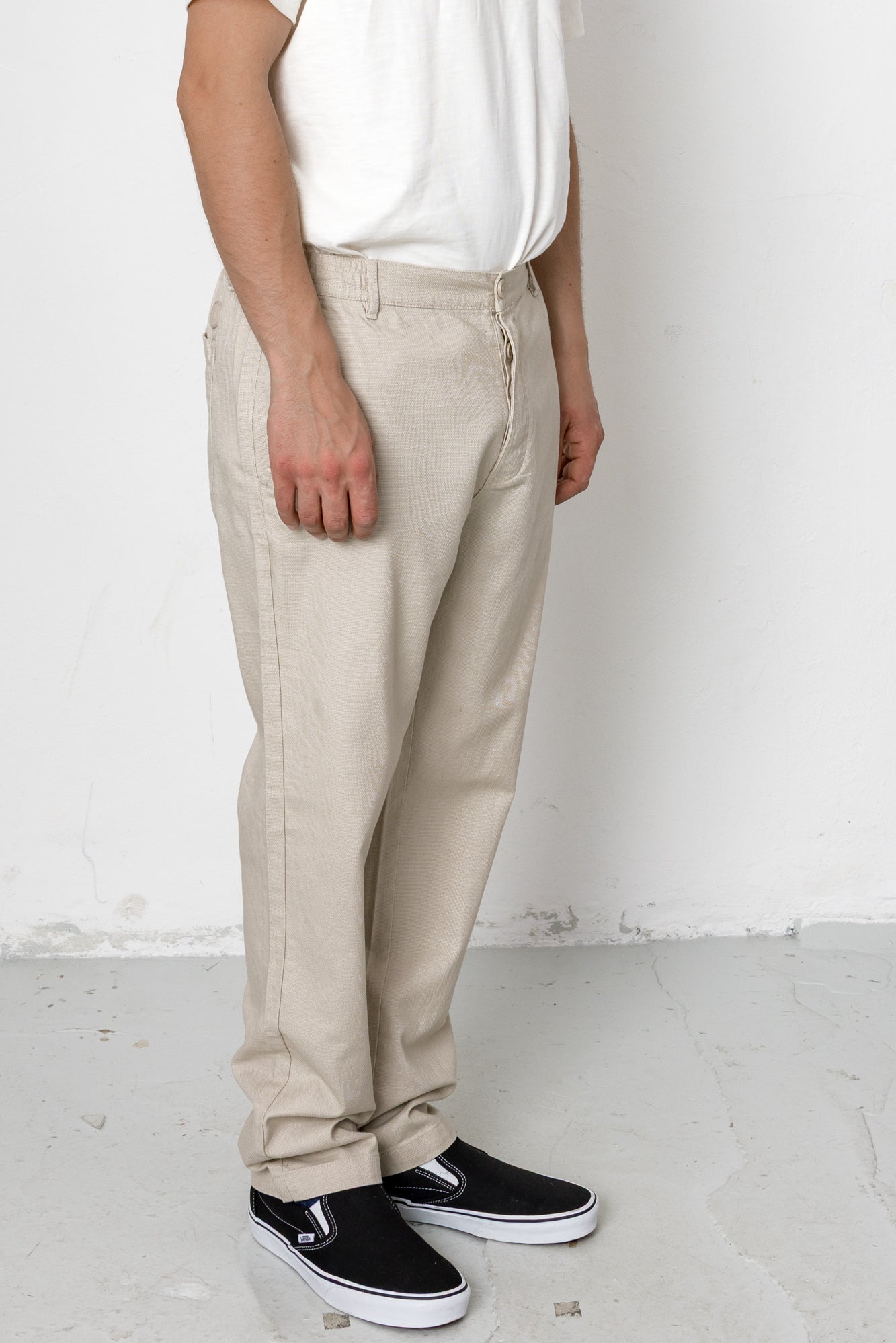 Person wearing beige pants and black shoes on a white background