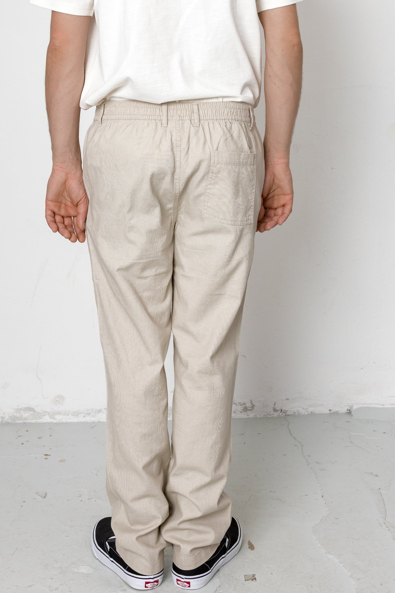 Person wearing beige pants and black sneakers on a white background