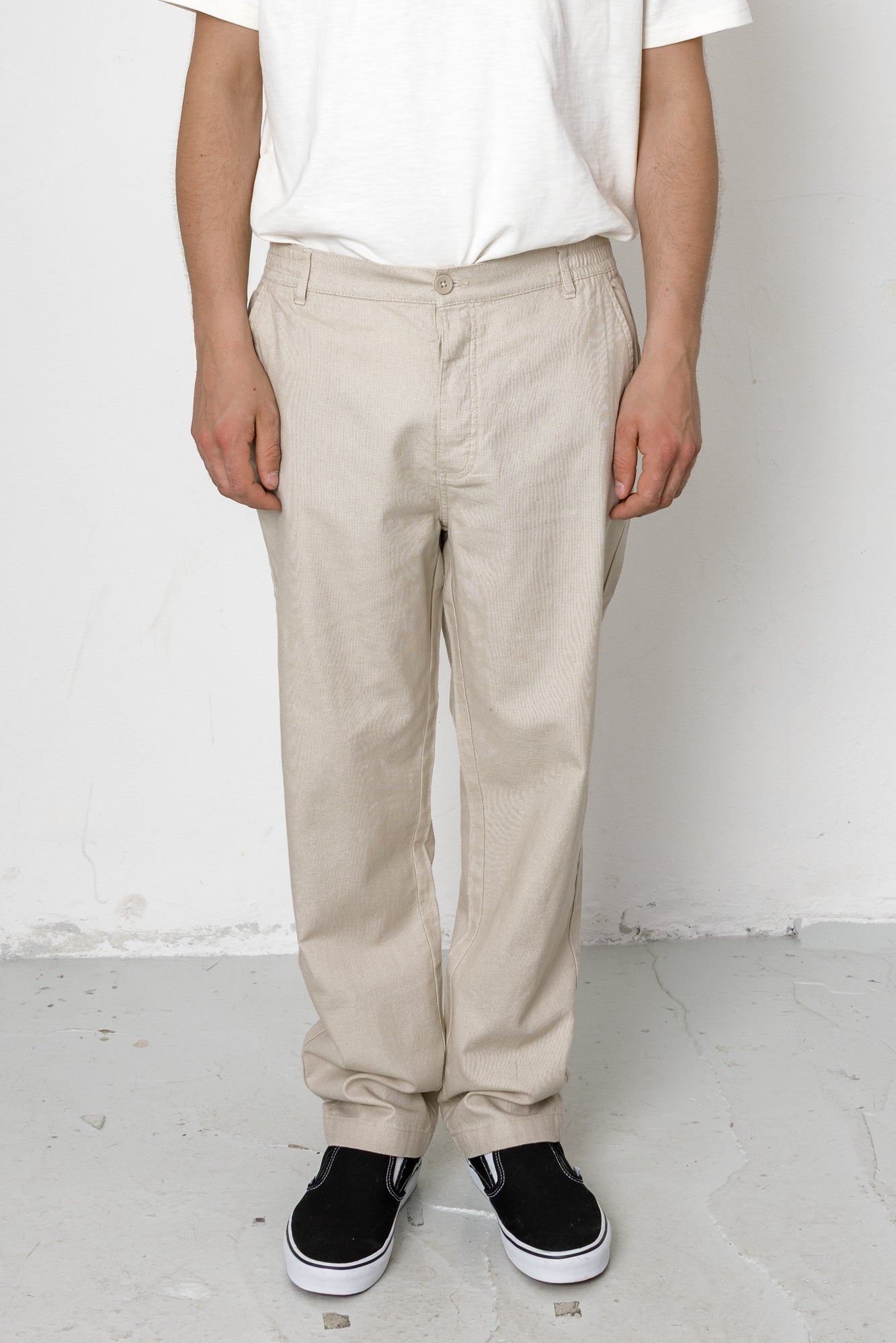 Person wearing beige pants and black shoes on a white background