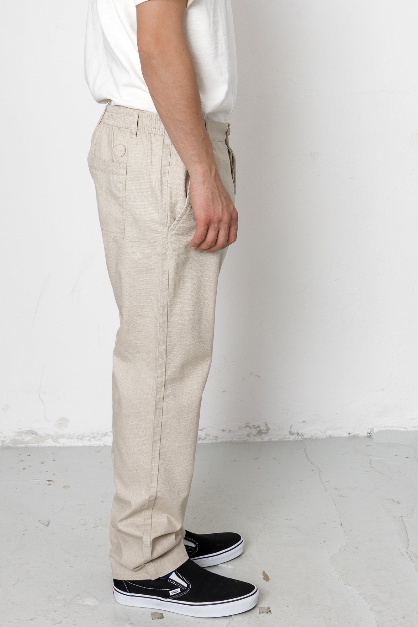 Person wearing beige pants and black shoes on a white background