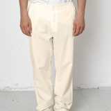 Person wearing white pants and black shoes on a plain background