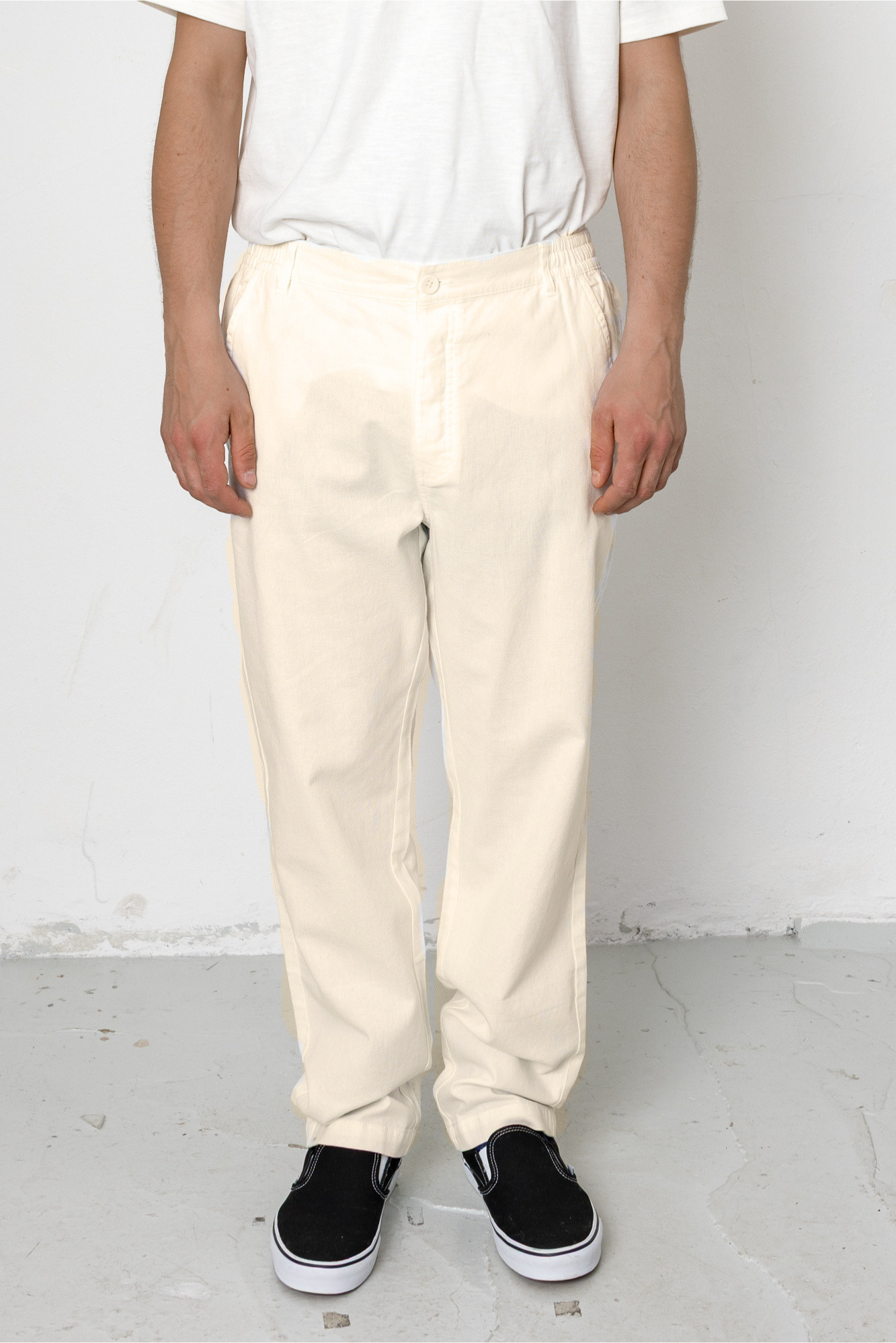 Person wearing white pants and black shoes on a plain background
