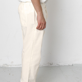 Person wearing white pants and black shoes on a plain background