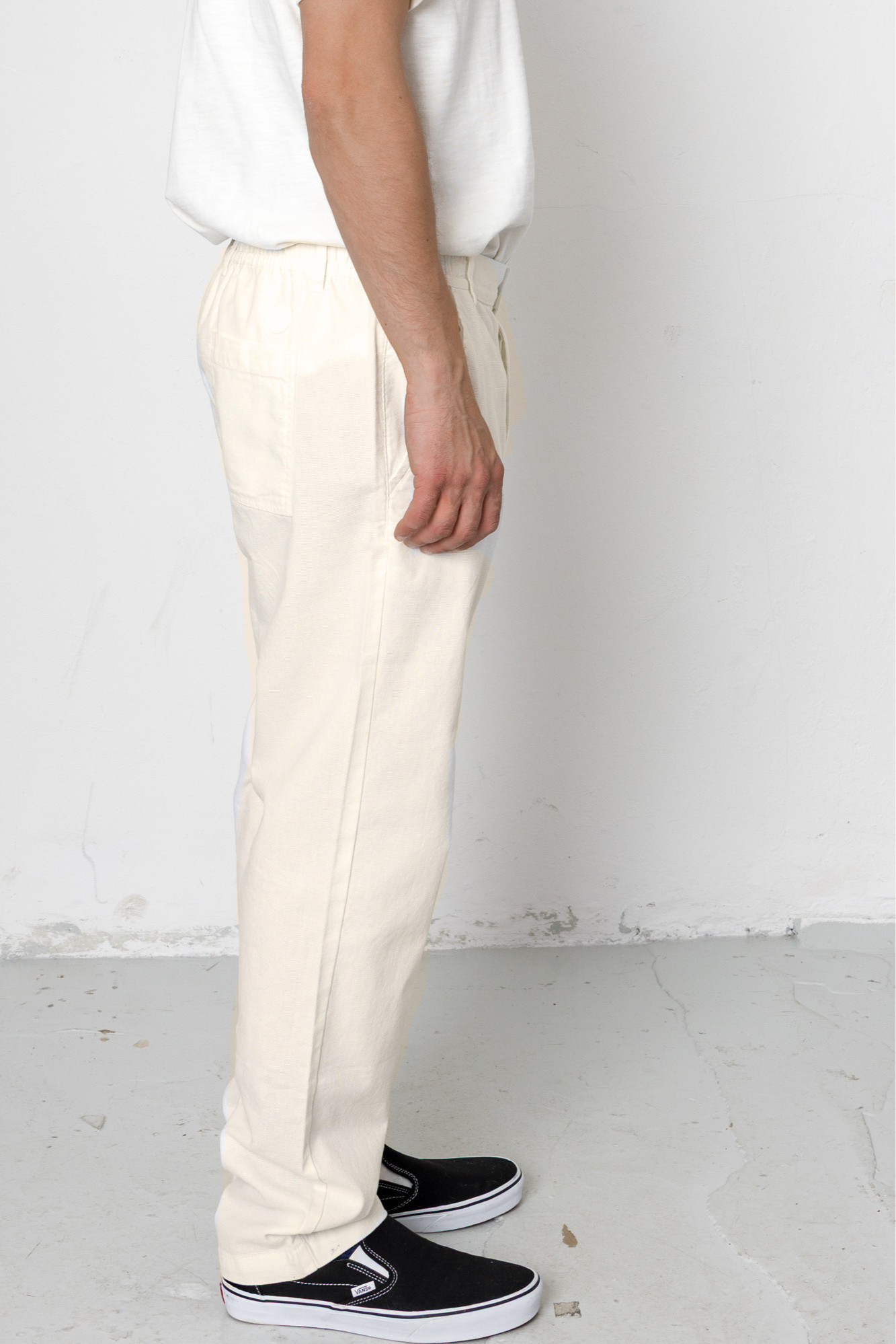 Person wearing white pants and black shoes on a plain background