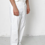 Person wearing white pants and black shoes against a plain background