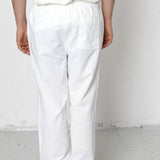 Person wearing white pants and a white shirt against a plain background