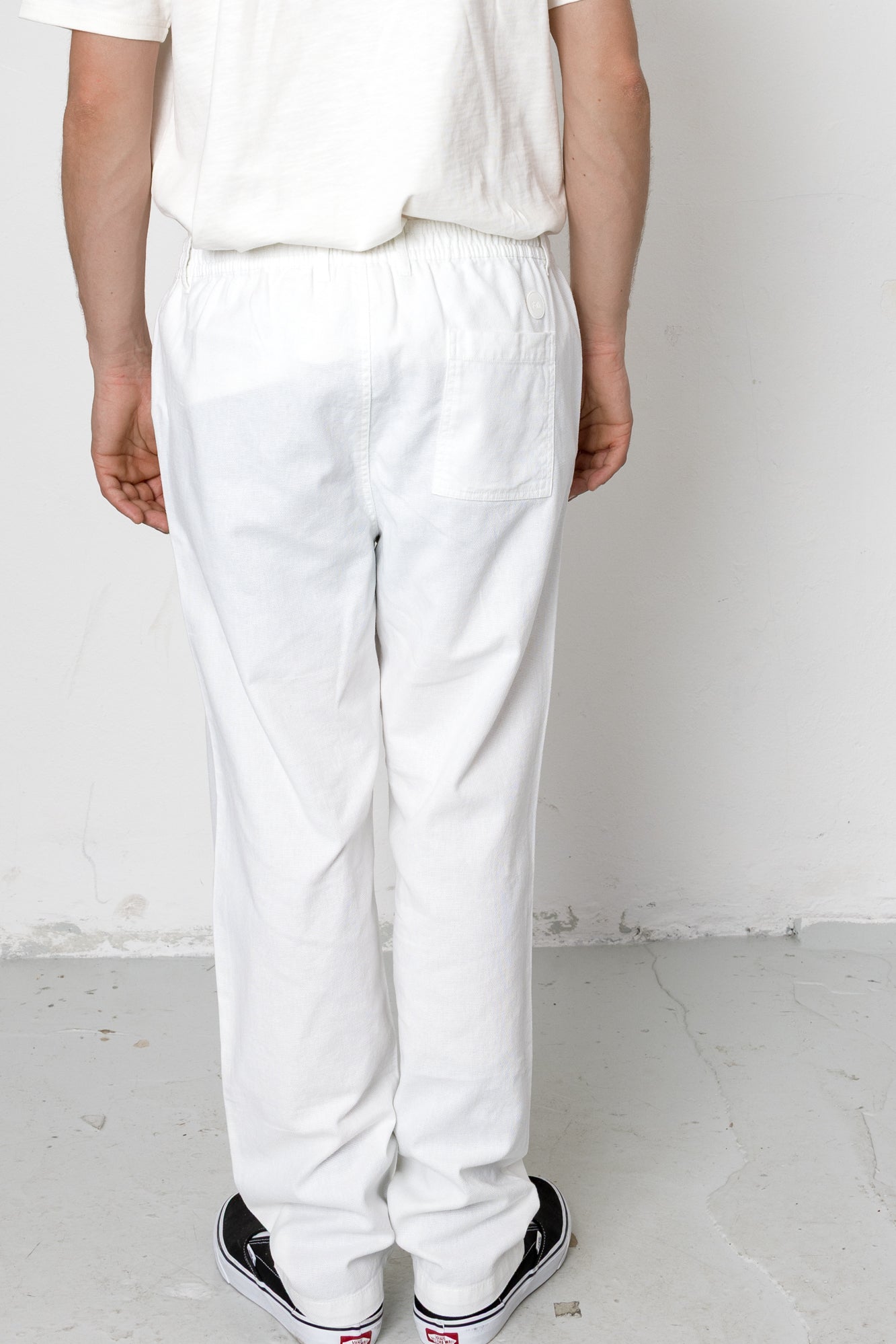 Person wearing white pants and a white shirt against a plain background