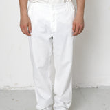 Person wearing white pants and black shoes on a plain background