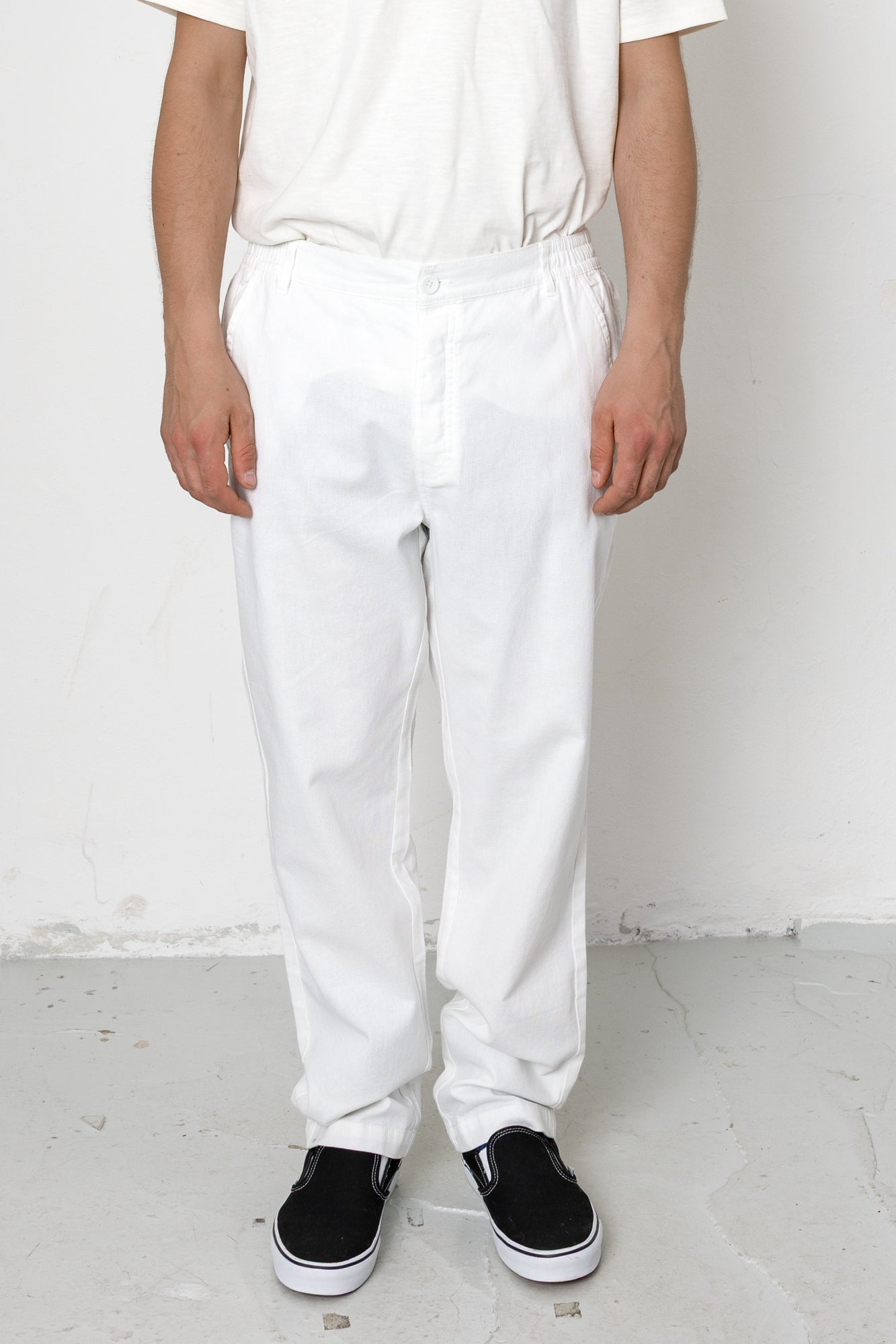 Person wearing white pants and black shoes on a plain background