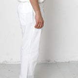 Person wearing white pants and black shoes on a plain background