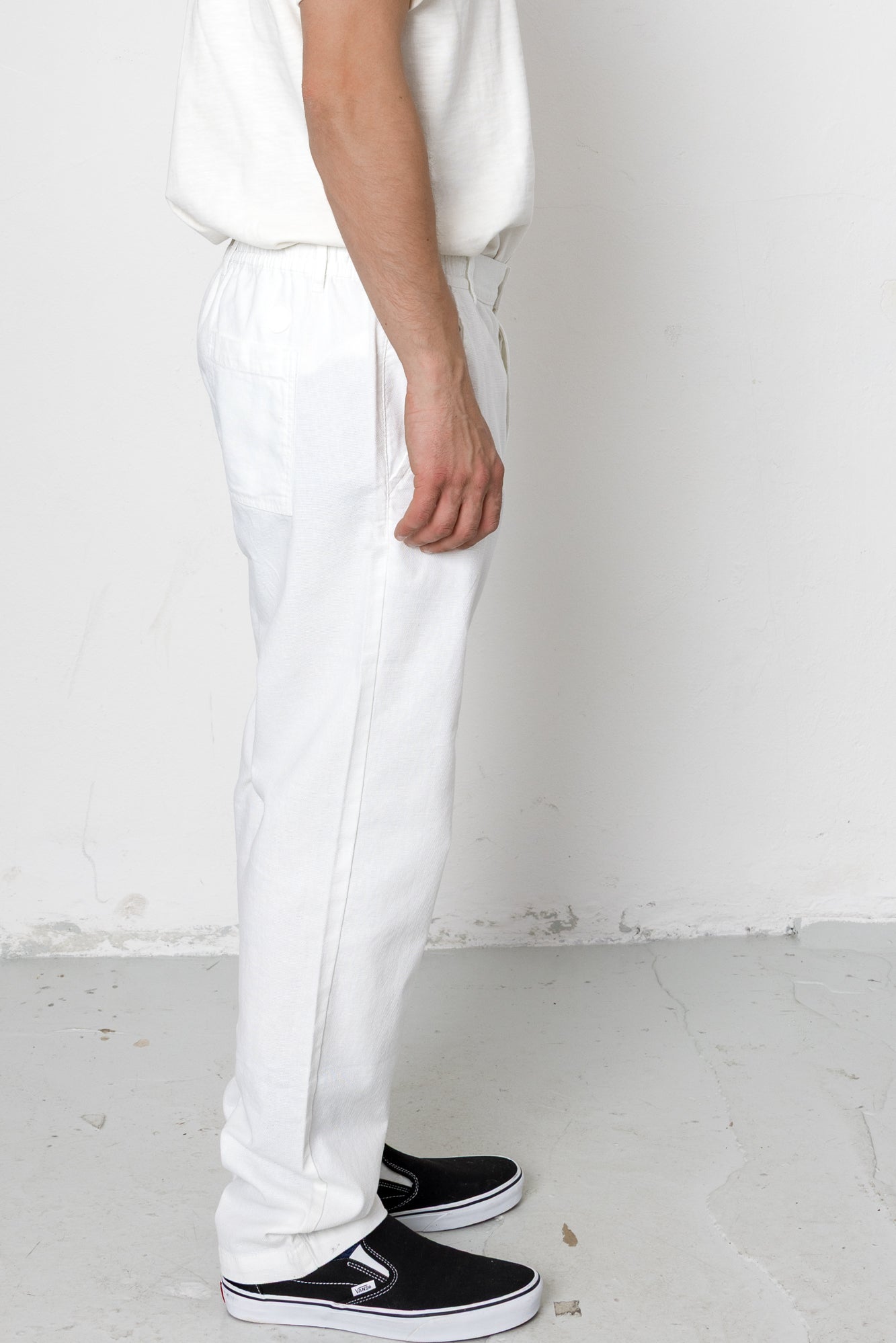 Person wearing white pants and black shoes on a plain background