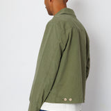 Person wearing a green jacket and blue jeans against a white background