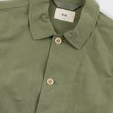 Green shirt with button details and 'Folk' label on a white background