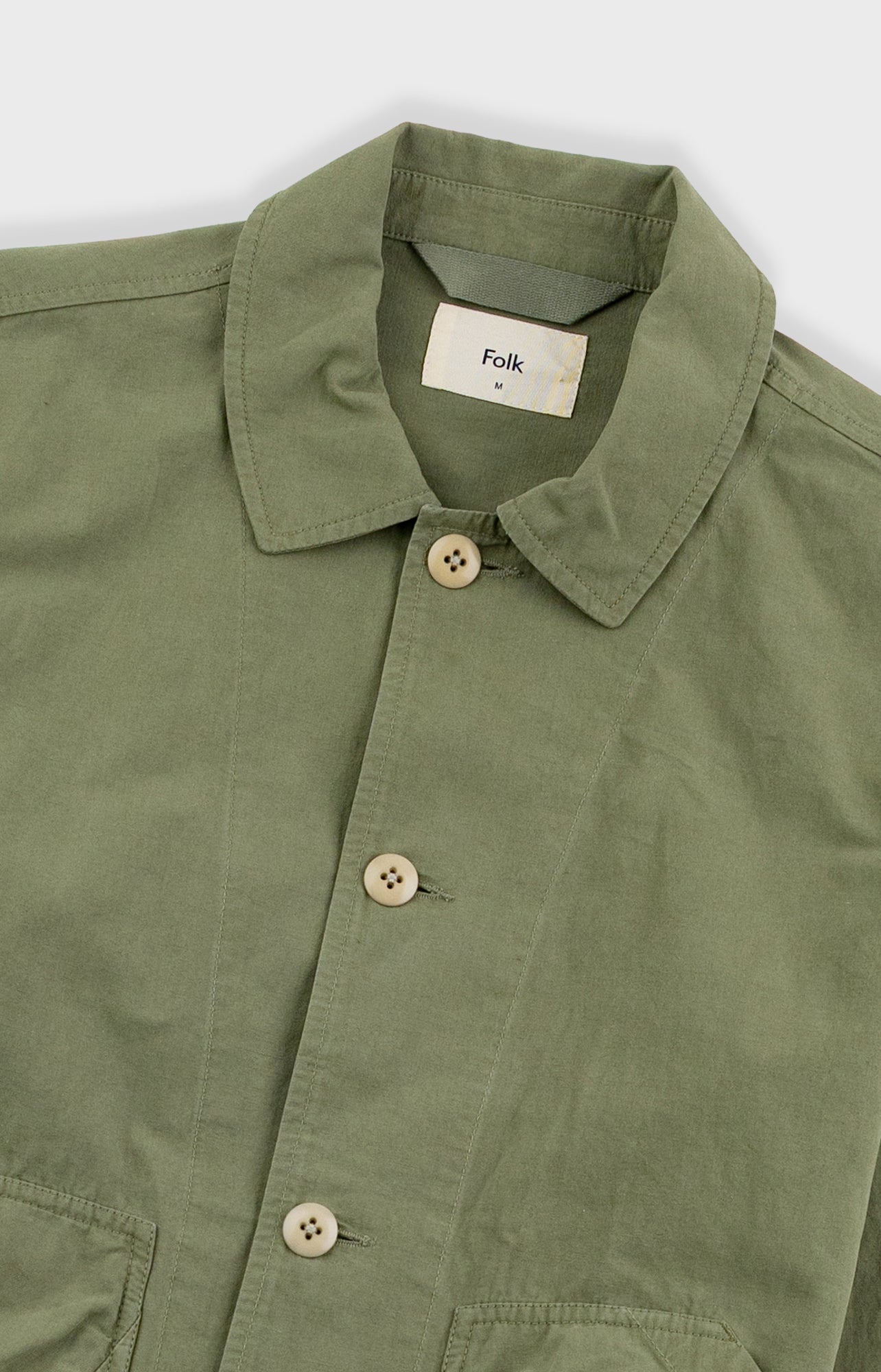 Green shirt with button details and 'Folk' label on a white background