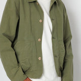 Person wearing a green jacket over a white shirt with a plain background