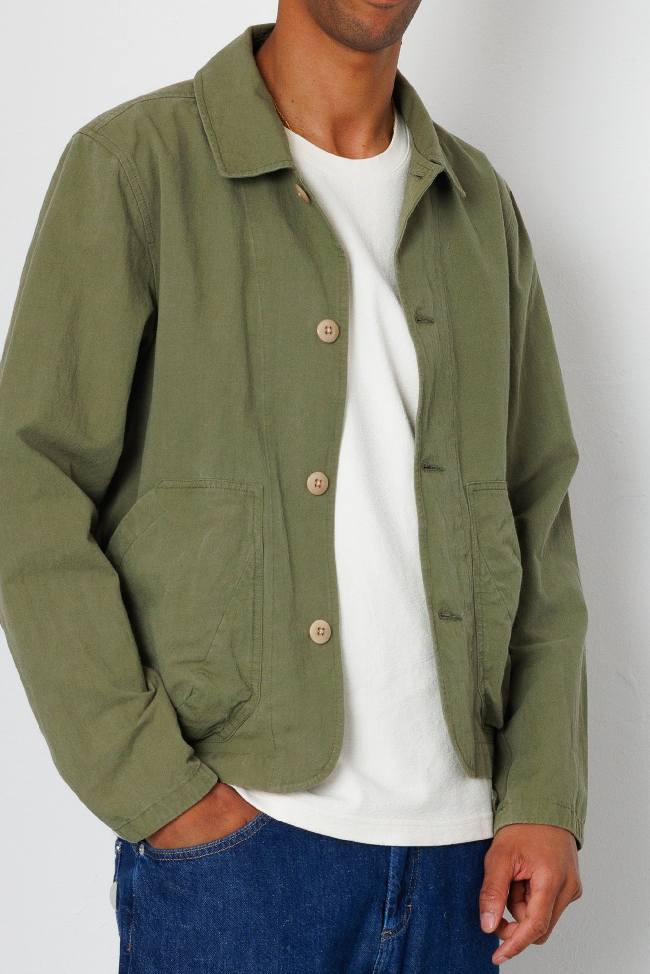 Person wearing a green jacket over a white shirt with a plain background