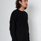 Man wearing a black long-sleeve shirt against a white background