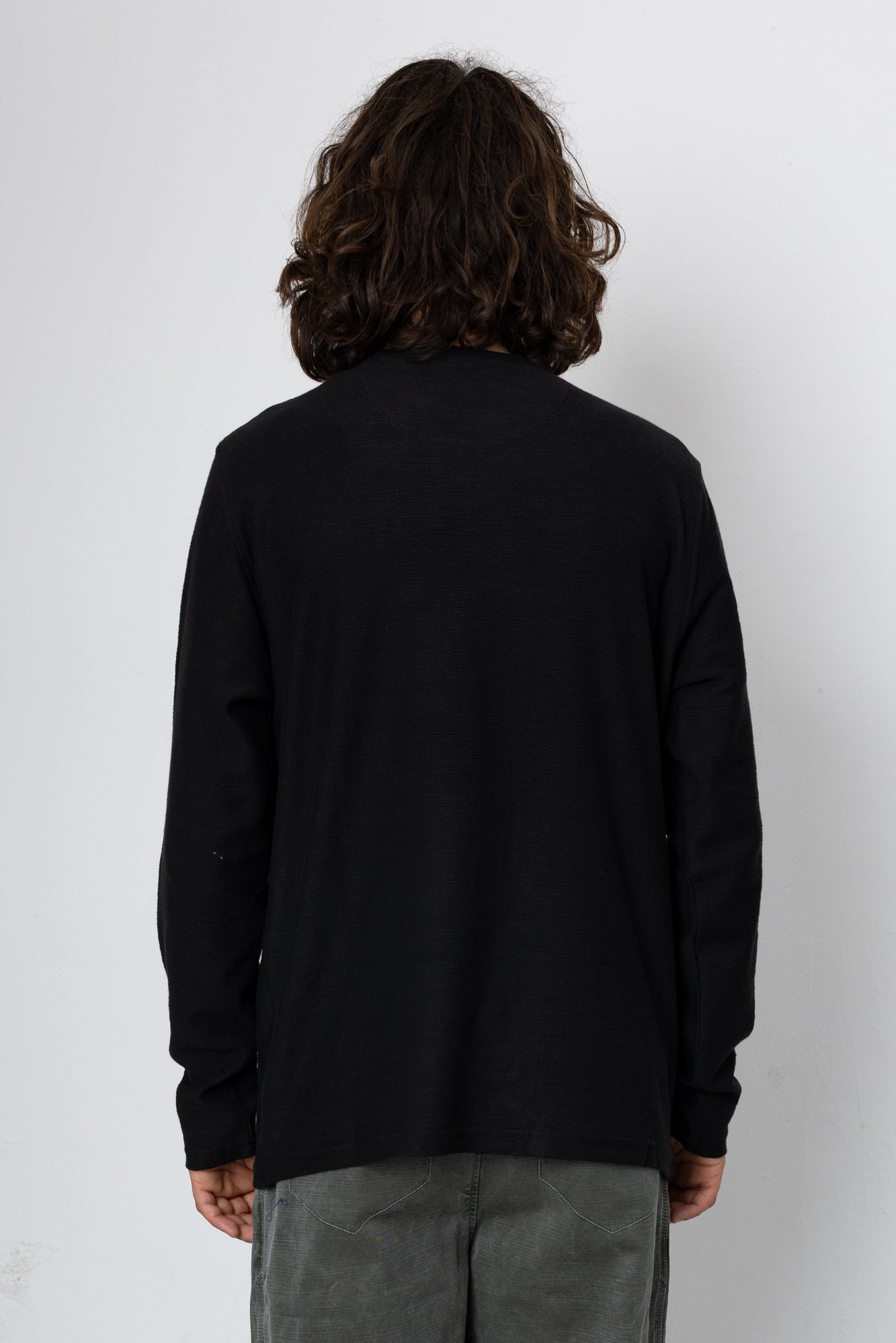 Person wearing a black long-sleeve shirt against a white background