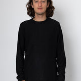 Person wearing a black long-sleeve shirt against a white background