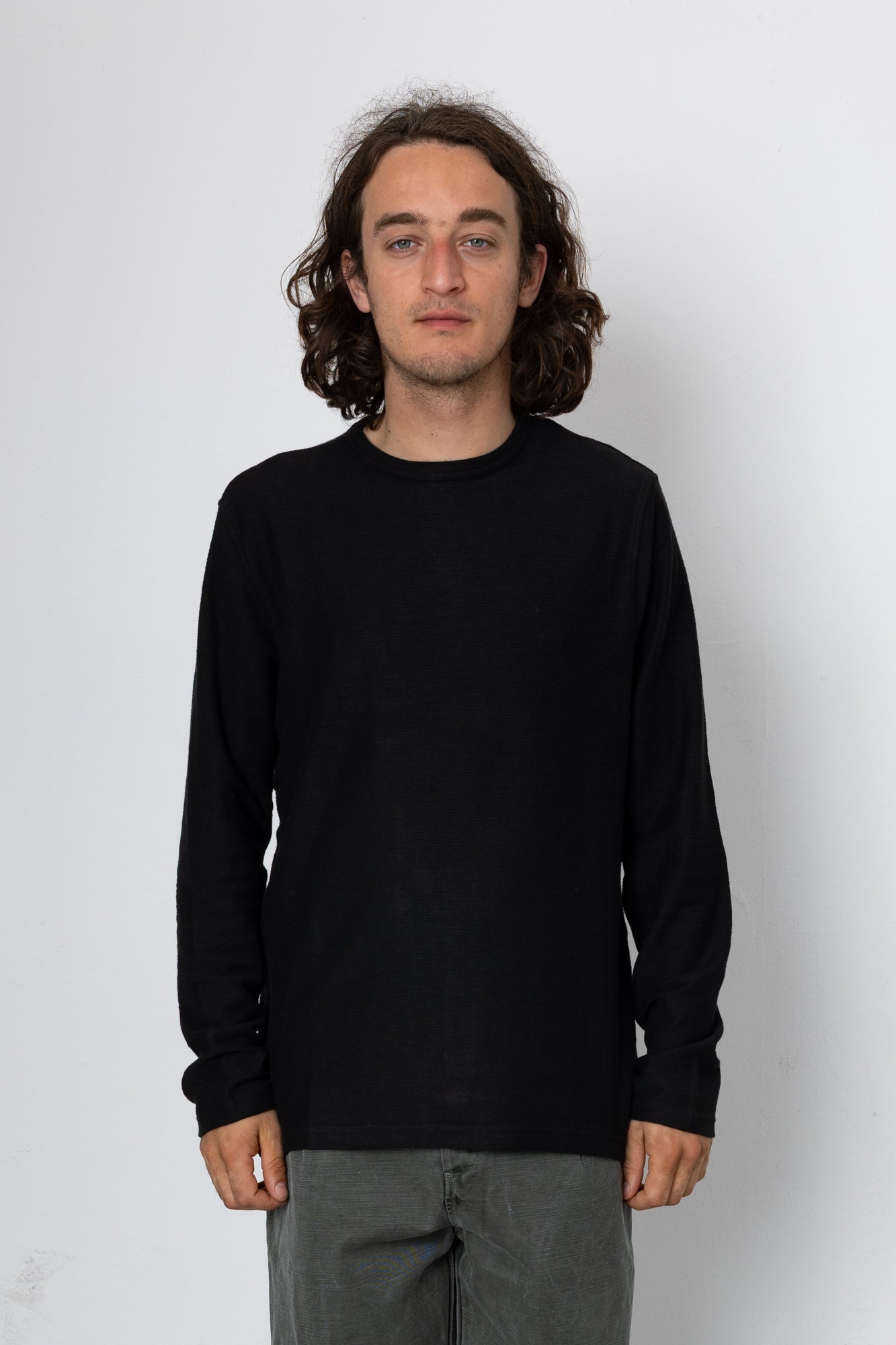 Person wearing a black long-sleeve shirt against a white background