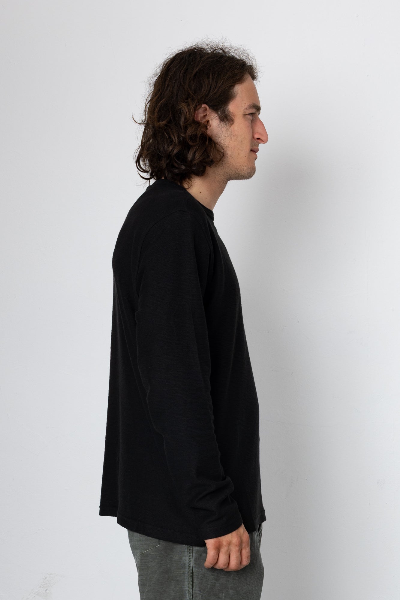 Person wearing a black long-sleeve shirt against a white background