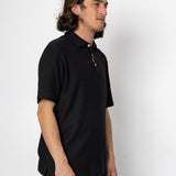 Man wearing a black polo shirt against a white background