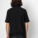 Person wearing a black shirt and pants against a white background