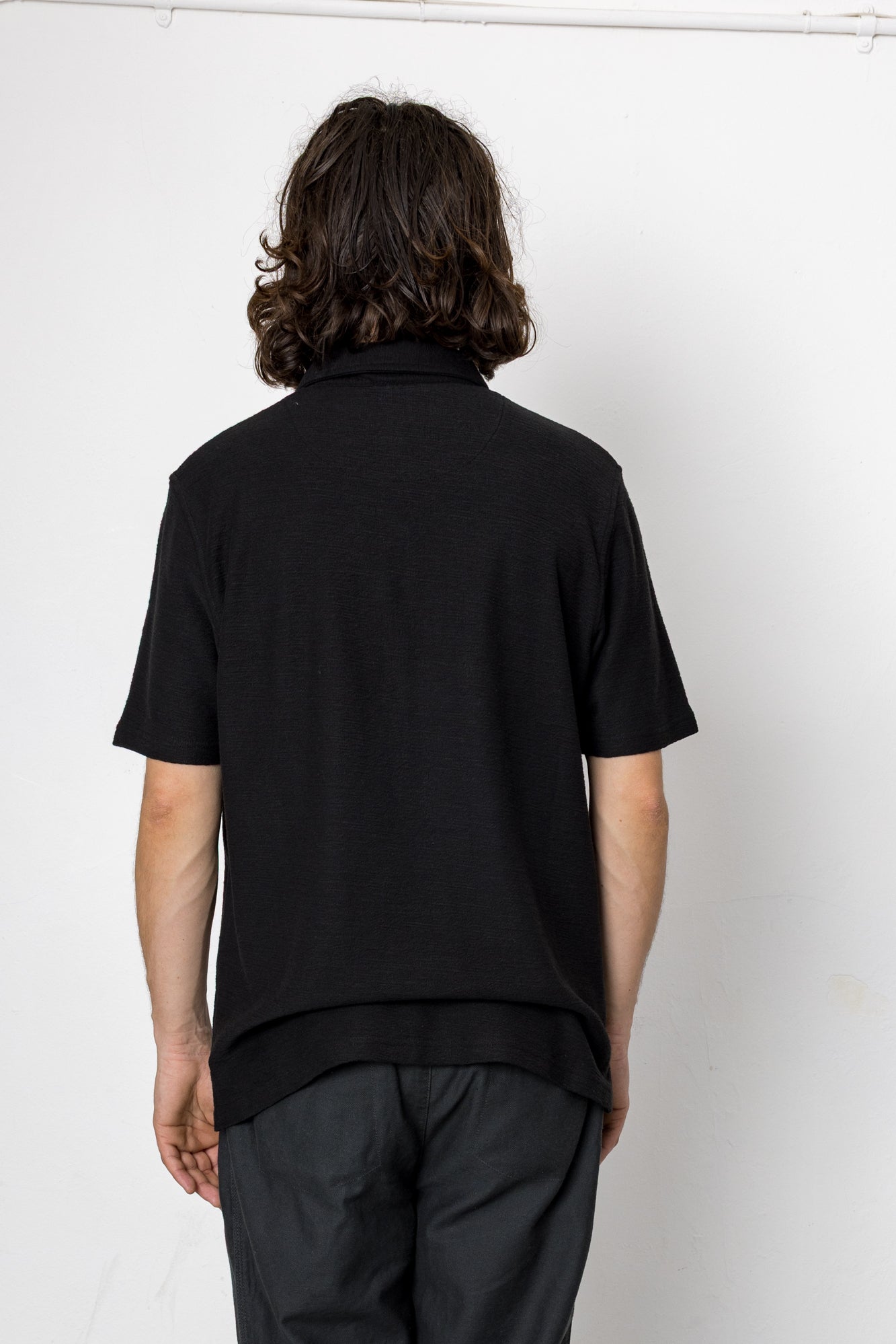 Person wearing a black shirt and pants against a white background