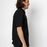 Man wearing a black shirt and pants against a white background