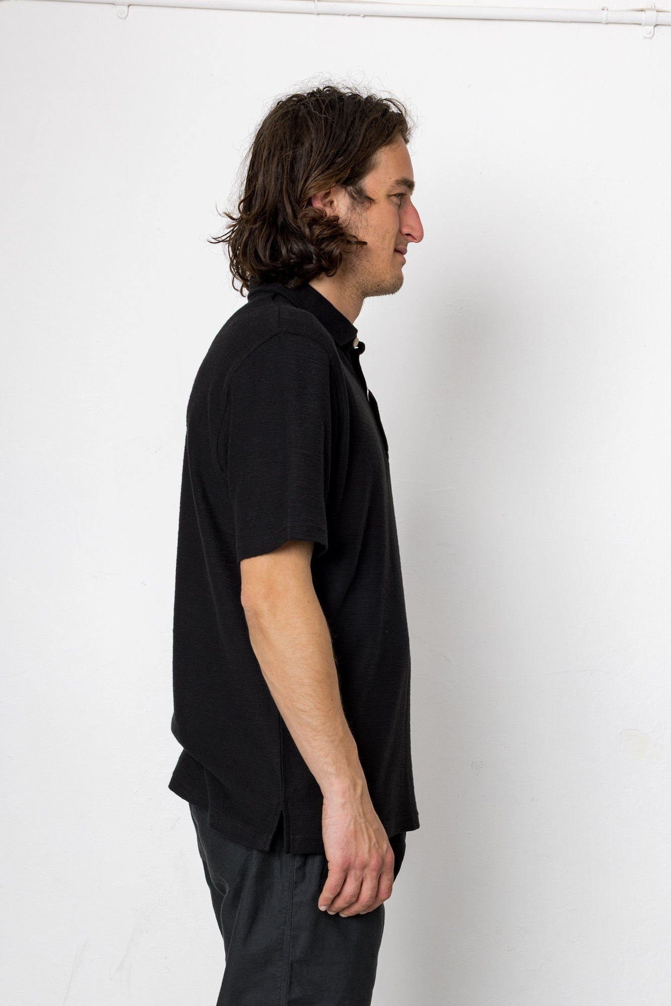 Man wearing a black shirt and pants against a white background