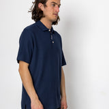 Man wearing a navy blue polo shirt against a white background