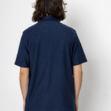Person wearing a navy blue polo shirt against a white background