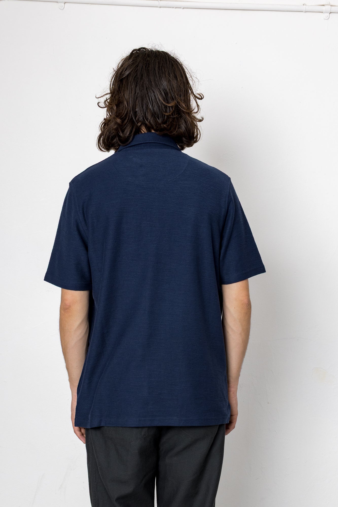 Person wearing a navy blue polo shirt against a white background