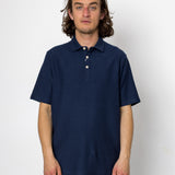 Person wearing a navy blue polo shirt against a white background