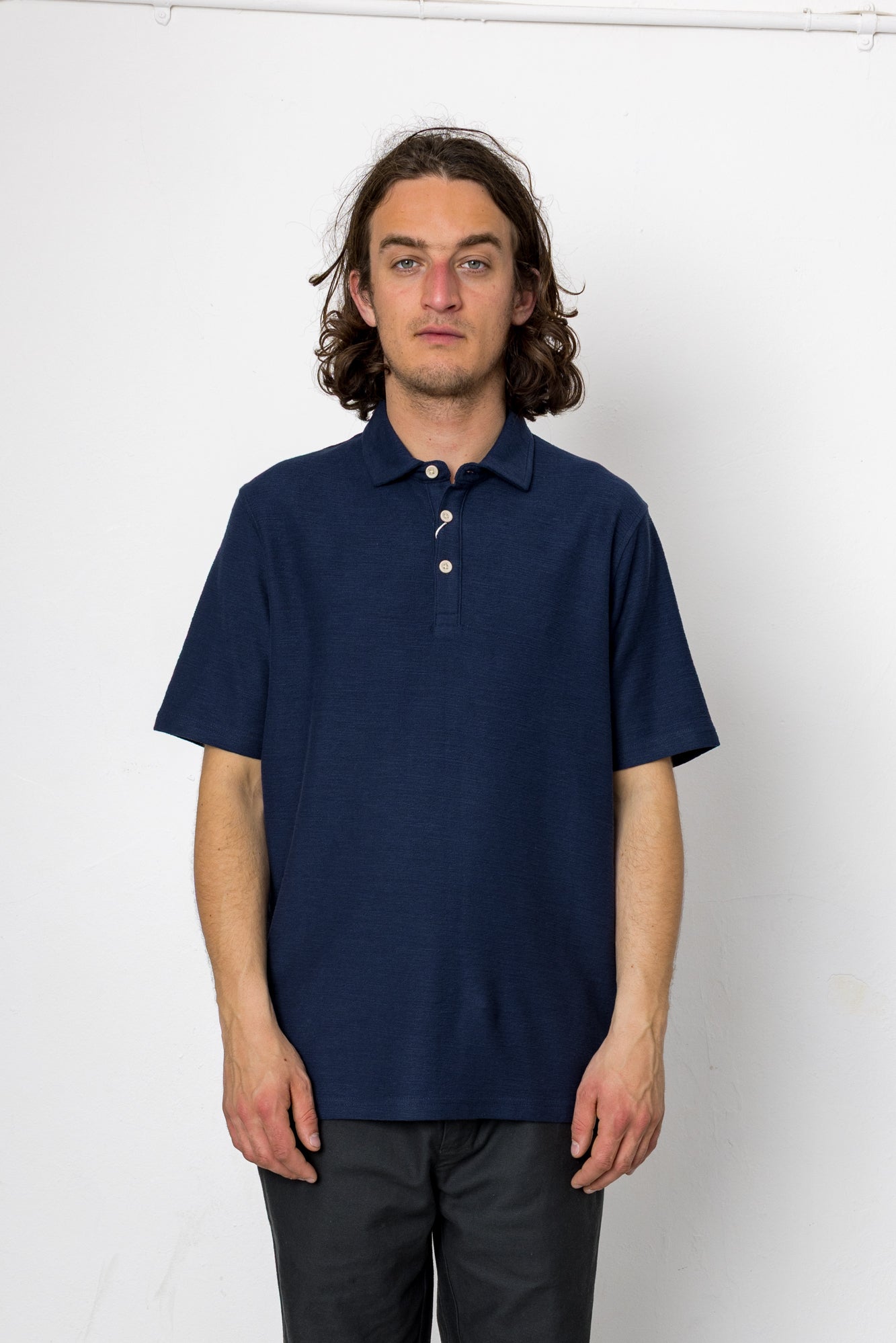 Person wearing a navy blue polo shirt against a white background