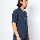 Man wearing a navy blue short-sleeve shirt against a white background