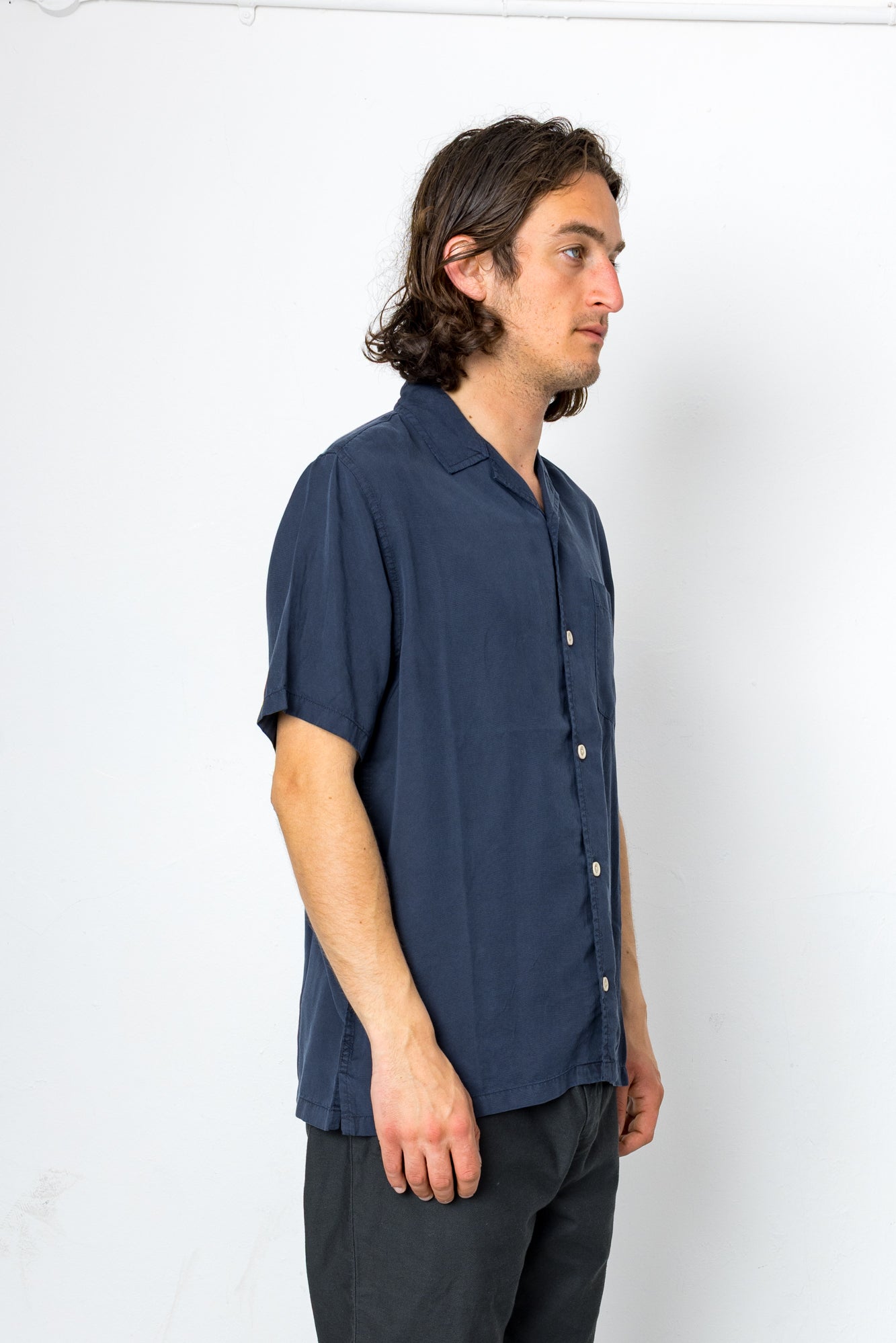Man wearing a navy blue short-sleeve shirt against a white background