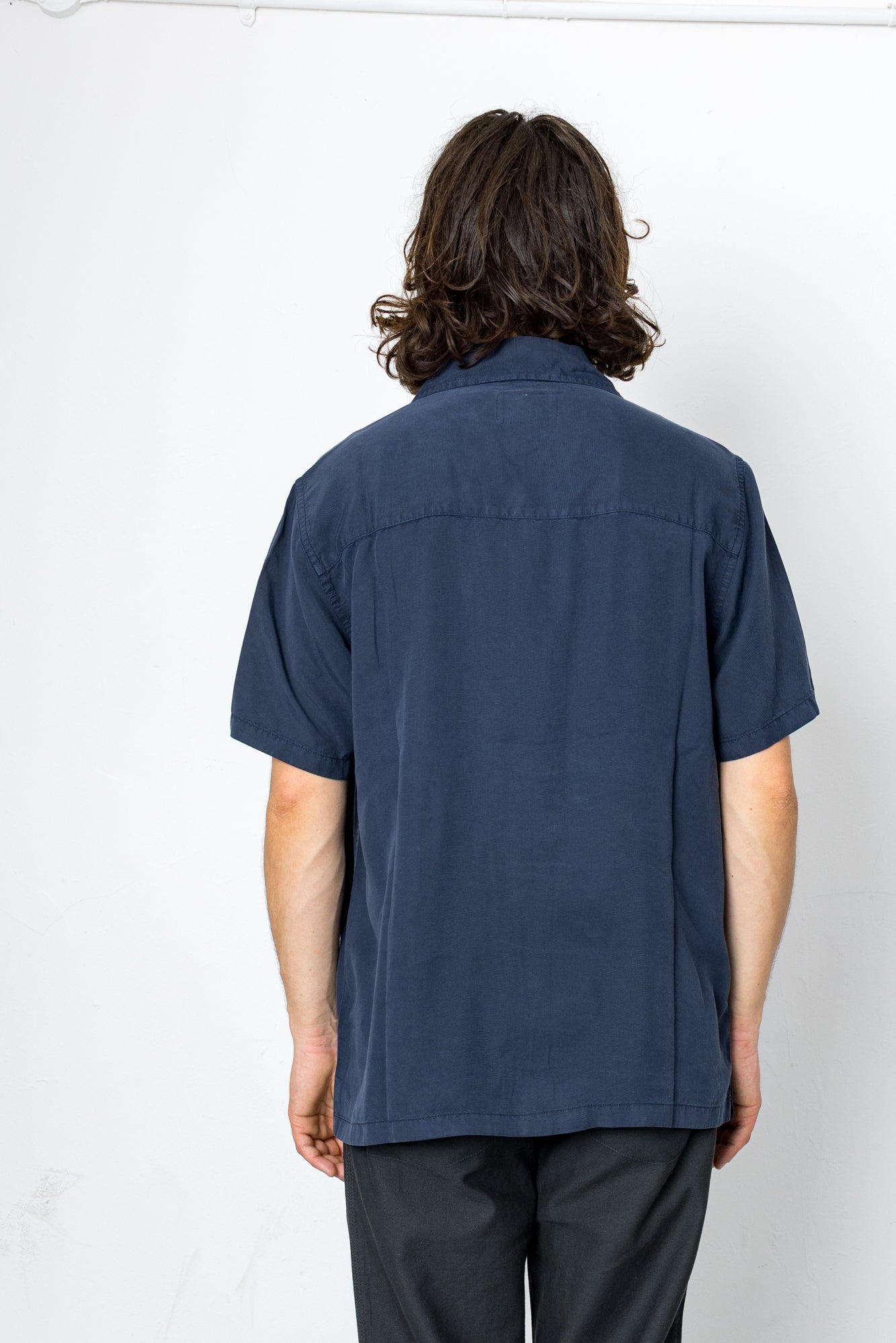 Person wearing a navy blue short-sleeve shirt on a white background