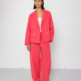 Person wearing a coral suit standing against a white background