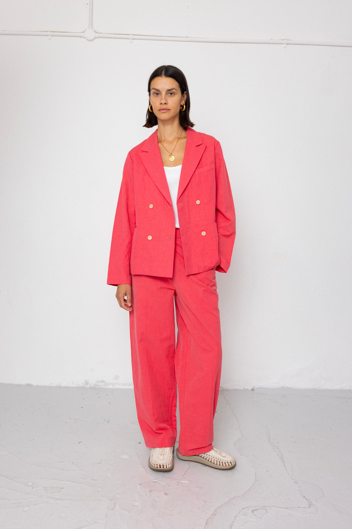 Person wearing a coral suit standing against a white background