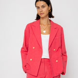 Woman wearing a coral suit against a white background