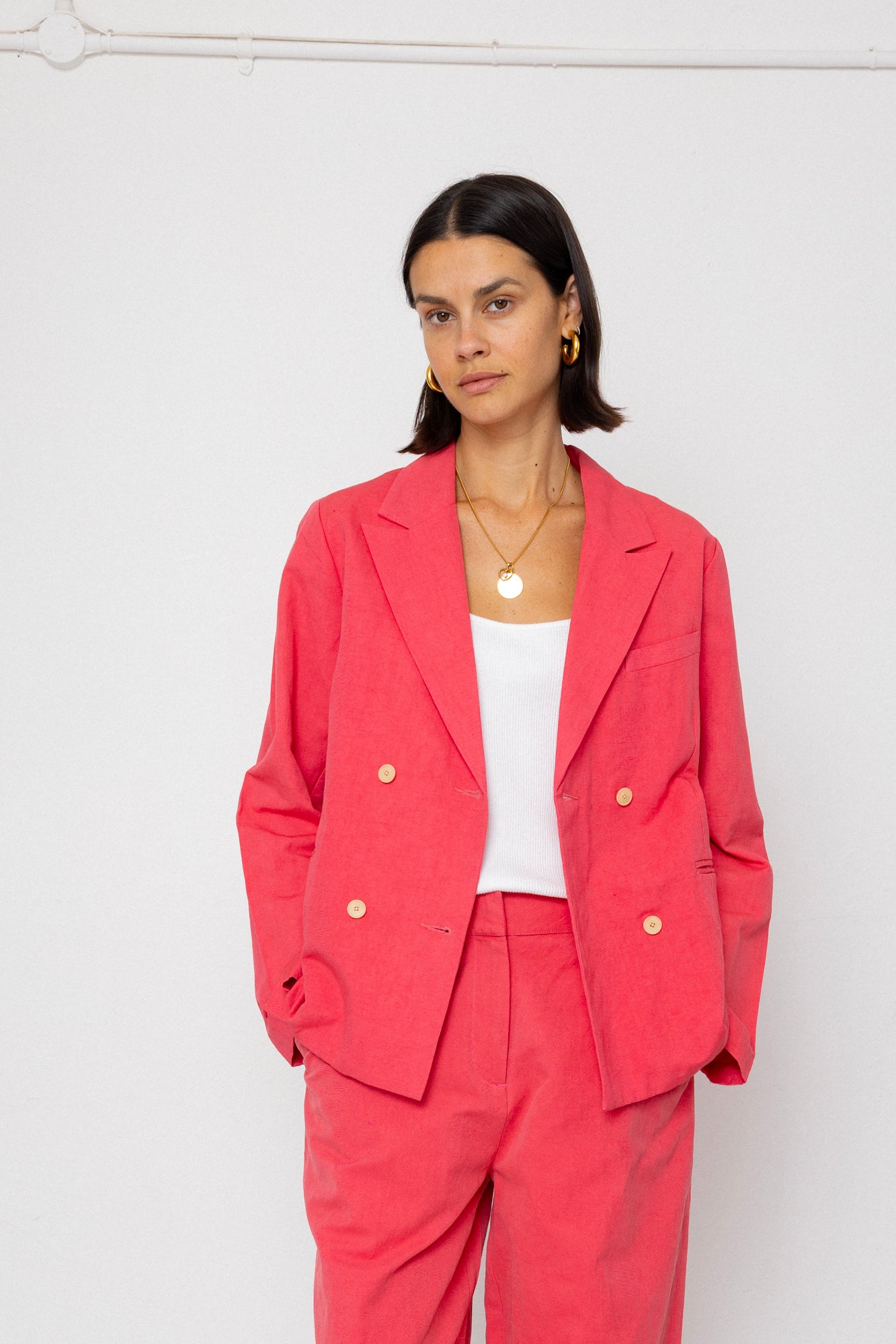 Woman wearing a coral suit against a white background