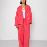 Woman wearing a coral suit against a white background