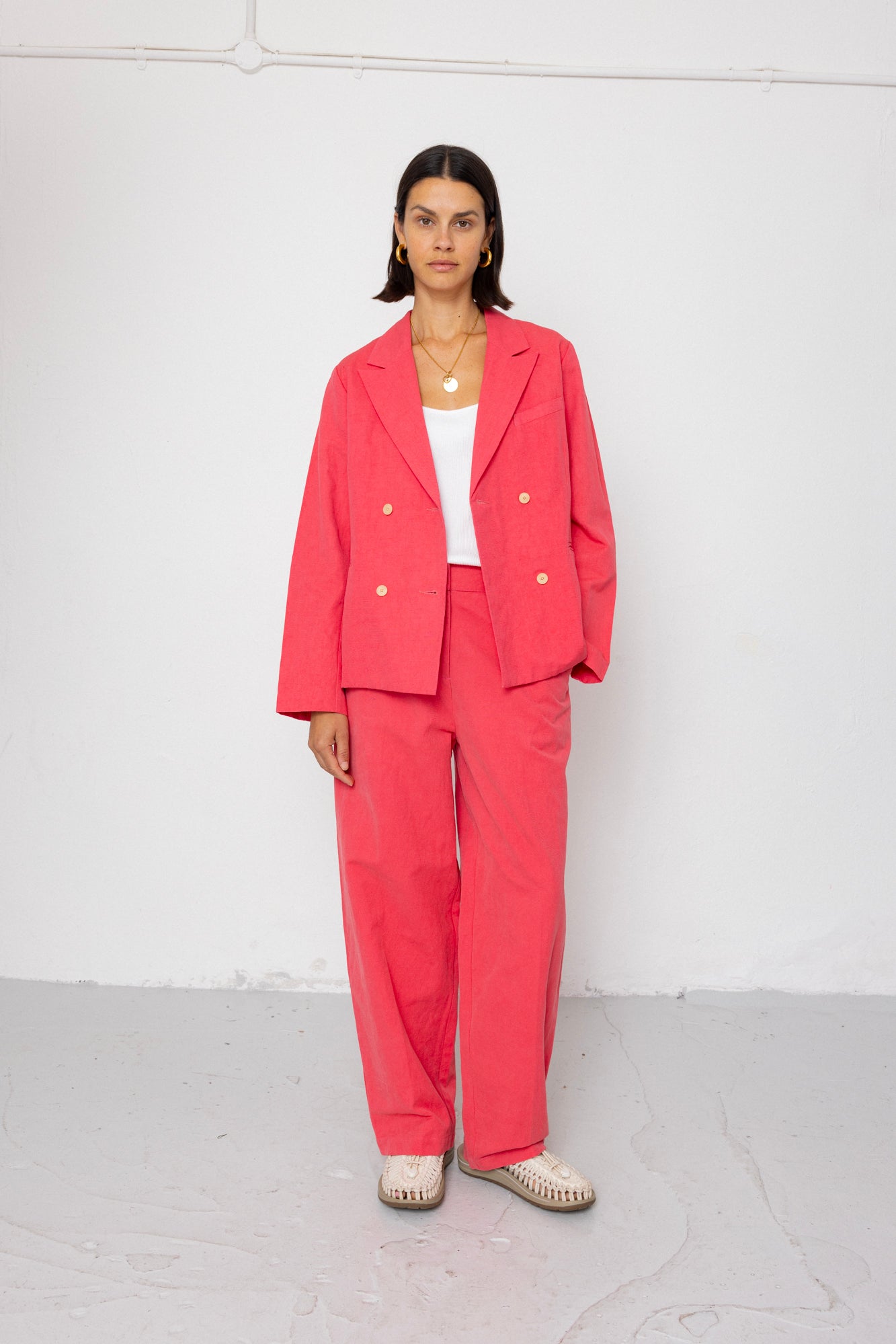 Woman wearing a coral suit against a white background