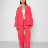 Woman wearing a coral suit standing against a white background
