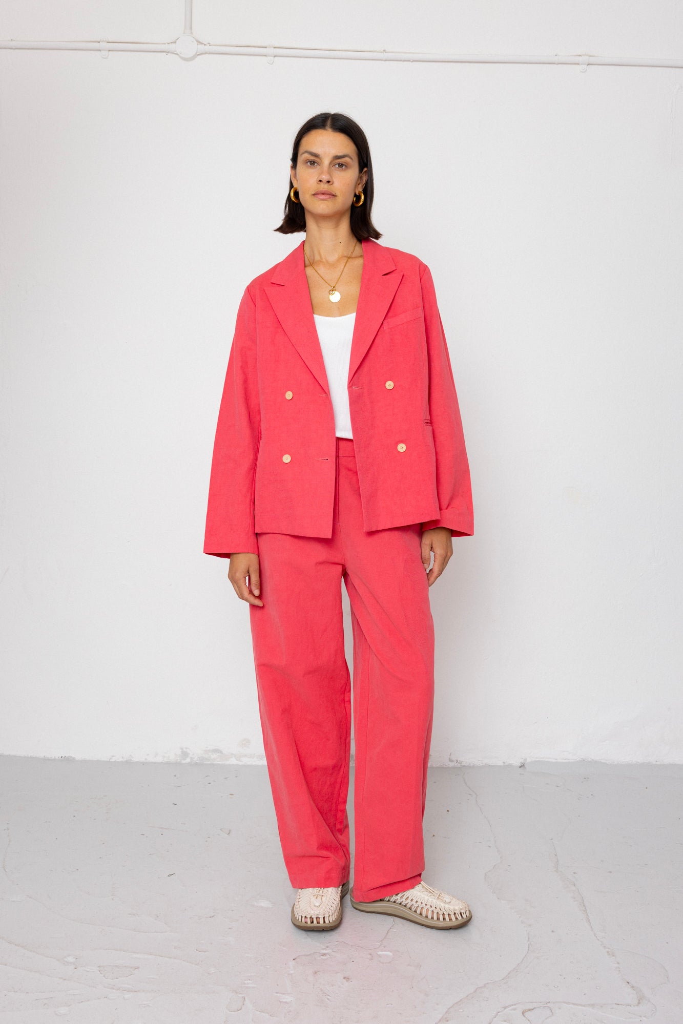 Woman wearing a coral suit standing against a white background