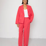 Person wearing a coral suit with a white top against a white background