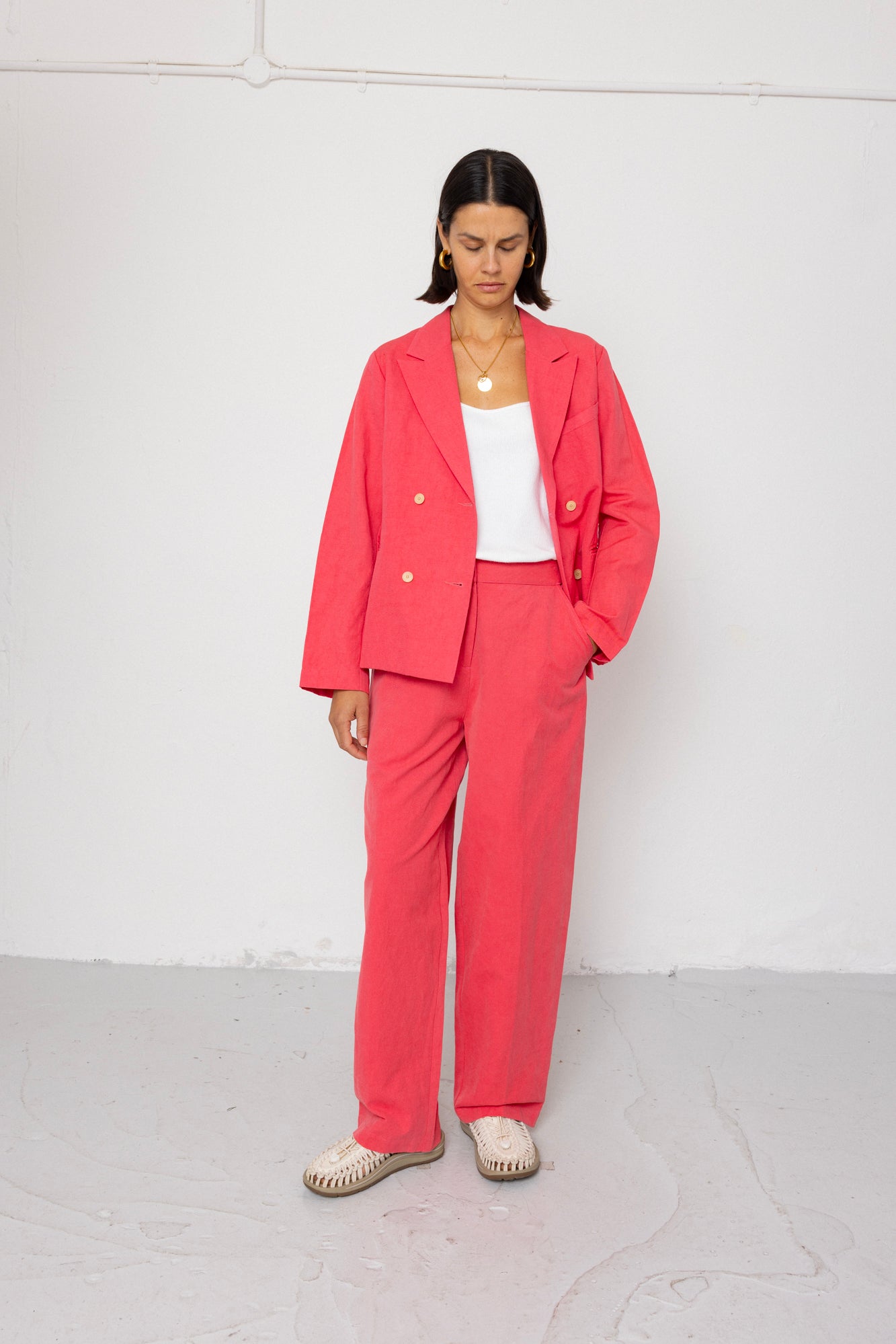 Person wearing a coral suit with a white top against a white background