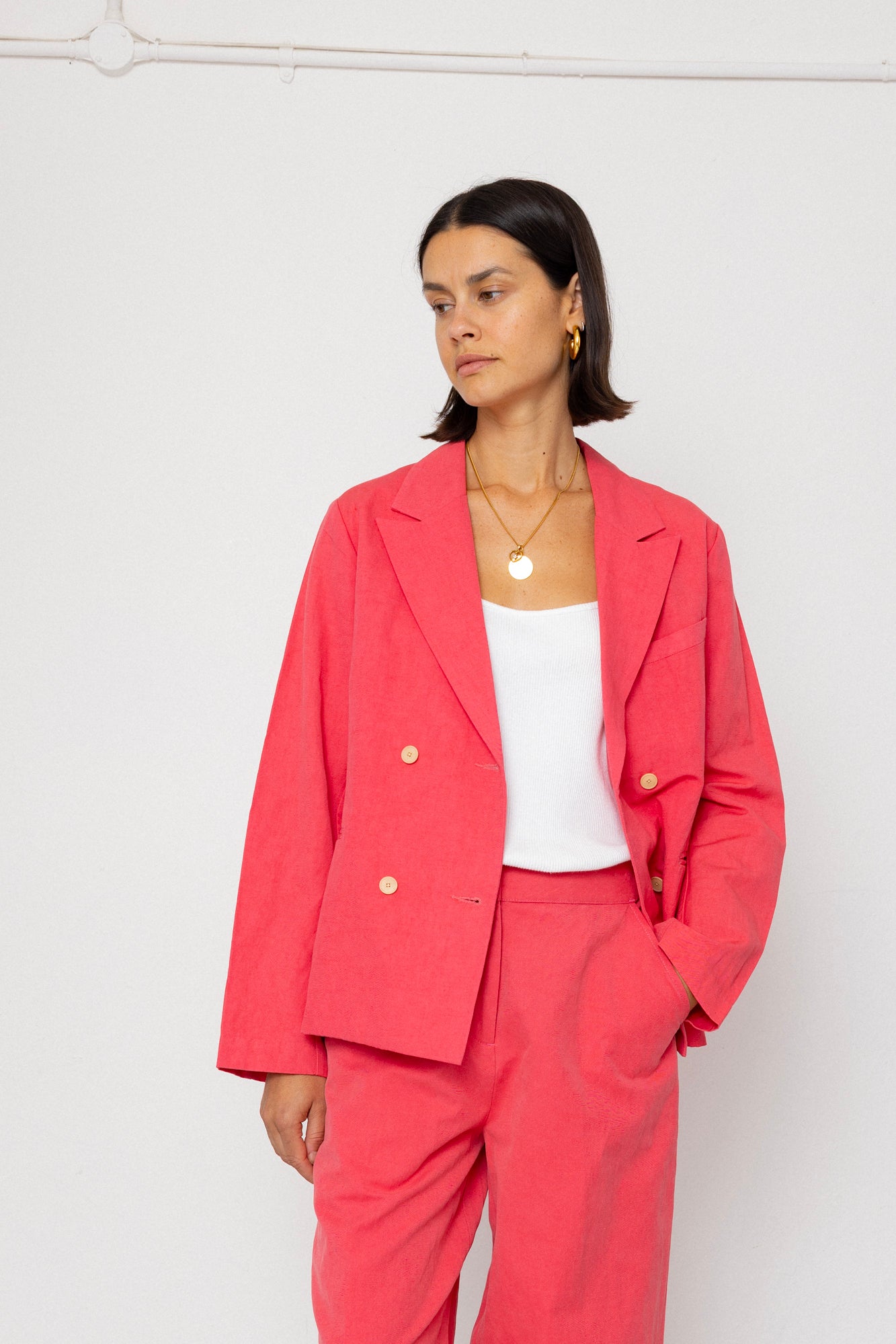 Woman wearing a coral suit with a white top against a white background