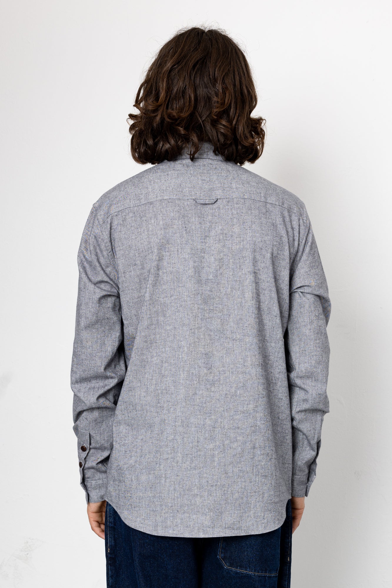 Person wearing a gray long-sleeve shirt against a white background